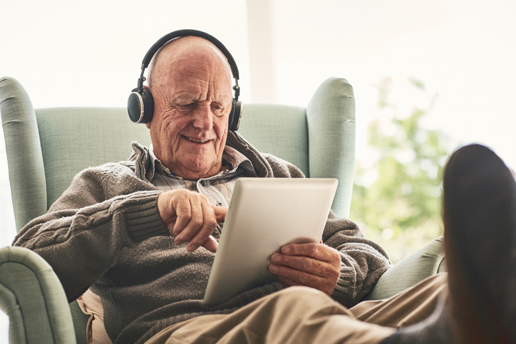 senior male with headphones and tablet