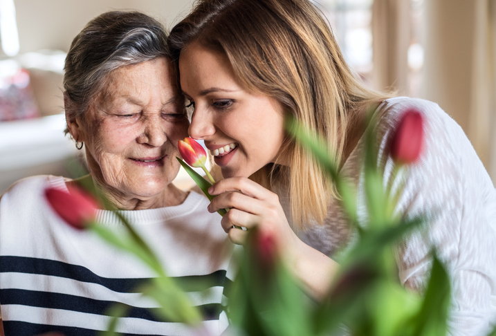 senior with family member smelling flowers