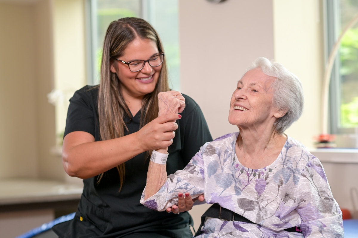Physical therapist working with female older adult on arm strengthening